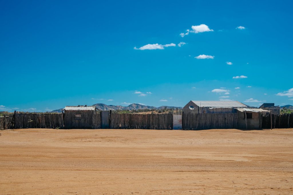 A desert area with a fence and a few buildings