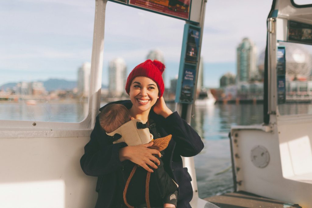 A woman wearing her baby in a carrier, travelling in a ferry boat.