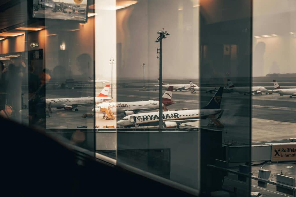 Airplanes at a bustling airport with reflections of interiors in the window panes.