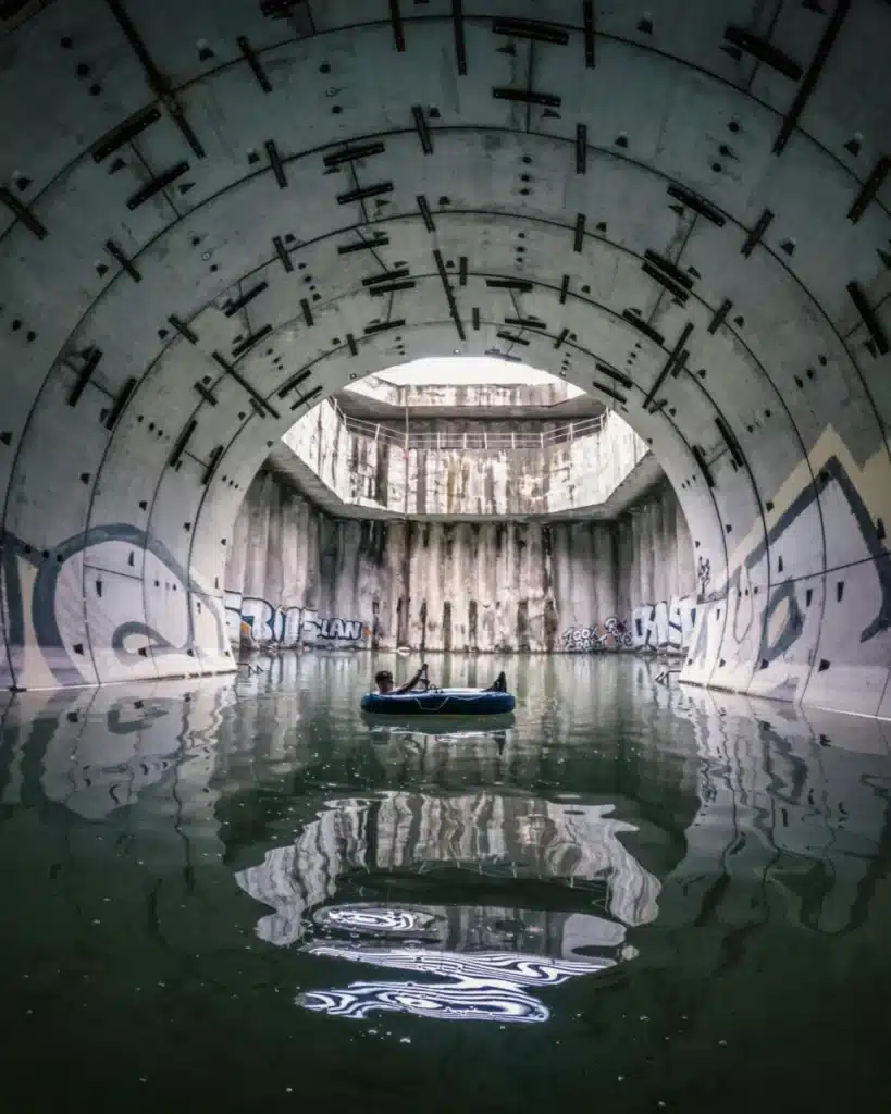 Côte d’Azur hors des sentiers battus : 6 adresses que Nice ne vous montrera jamais A man lies on a raft in a flooded sewage tunnel, surrounded by urban graffiti.