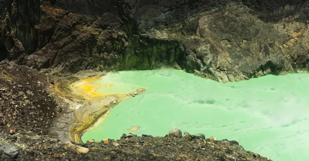 Santa Ana (Volcán Ilamatepec) en couple : la randonnée au volcan, sans se cramer ni se stresser A breathtaking view of a vibrant green sulfuric volcanic crater lake surrounded by rugged terrain.