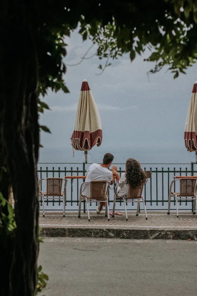 A couple sitting and talking on a terrace overlooking the sea, creating a romantic atmosphere.