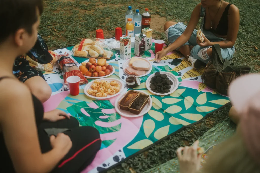 A group enjoying a variety of snacks during an outdoor picnic on a colorful blanket.