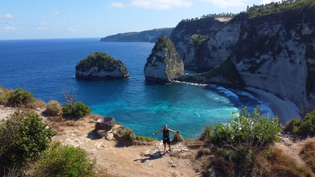 A hiker enjoying the stunning coastal cliffs and blue waters of Nusa Penida, Indonesia.