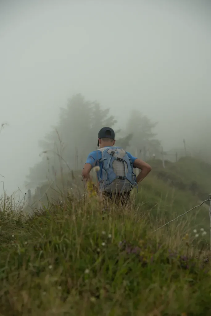 A lone hiker walks through a fog-shrouded mountain trail in Engelberg, Switzerland.
