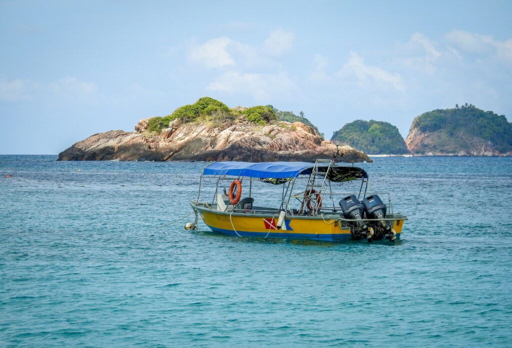 A peaceful seascape featuring a motorboat and islands under a clear sky.