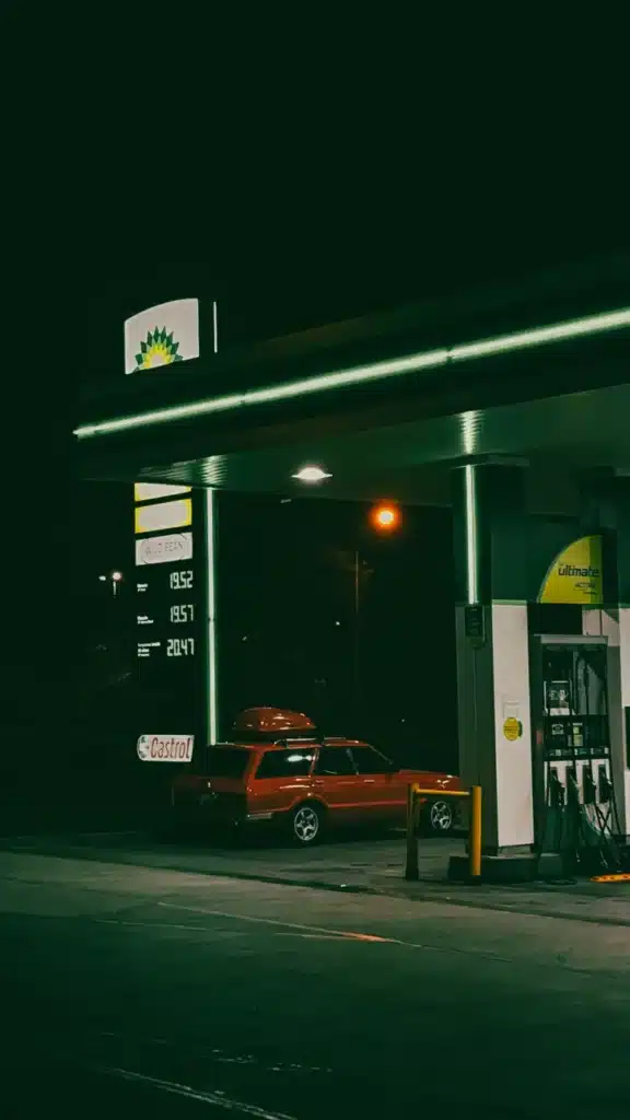 A red car at a BP gas station during the night, featuring a dimly lit atmosphere.