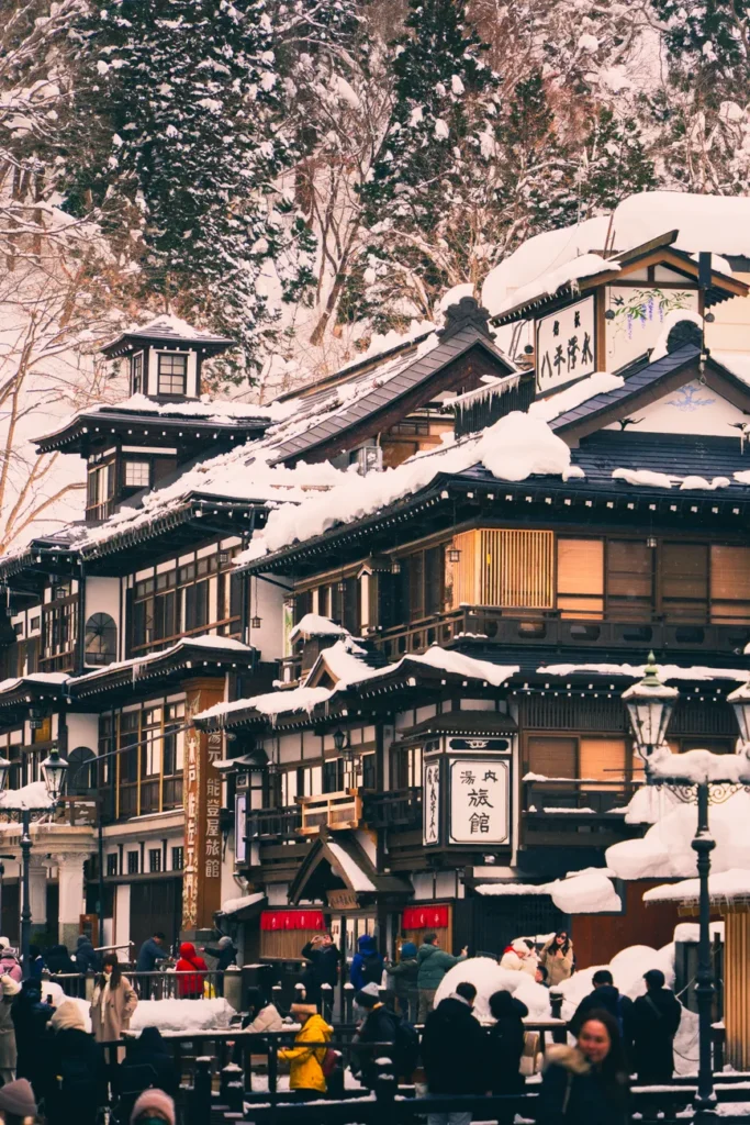 A scenic view of a traditional Japanese onsen surrounded by snow-covered trees, capturing seasonal beauty.
