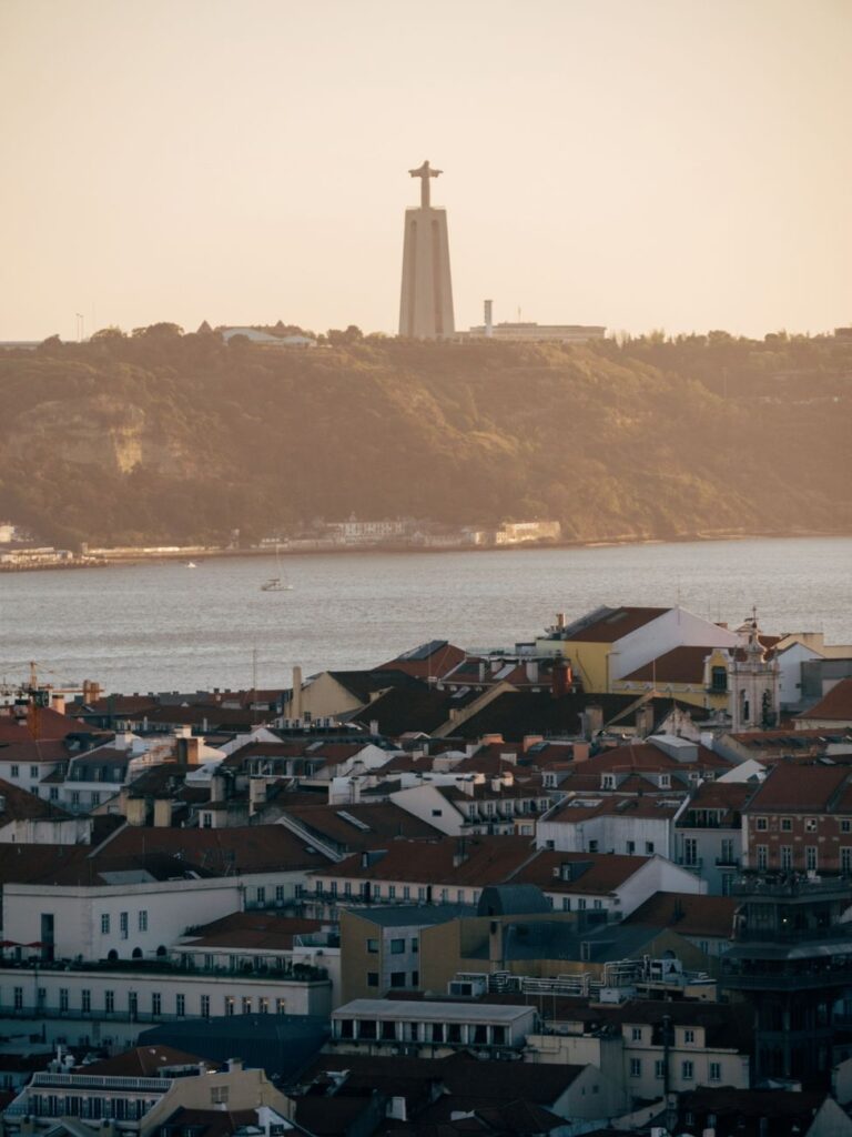 A stunning view over Lisbon with the Cristo Rei statue in warm sunset light, reflecting architectural charm.