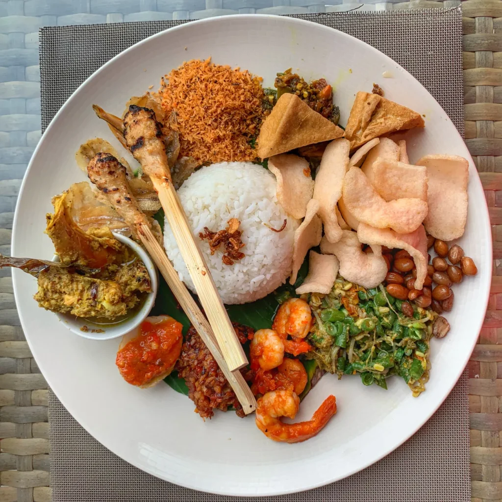A vibrant plate of traditional Nasi Campur in Bali, featuring rice, sate, and sambal.