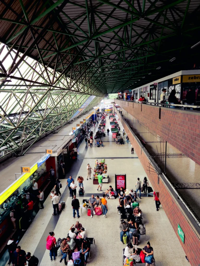 A vibrant scene at Medellín's bus terminal filled with travelers of all ages and backgrounds.
