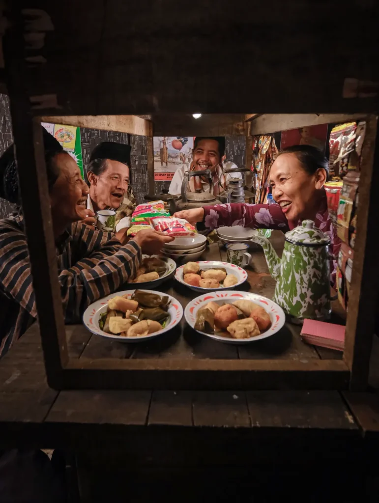 Adults sharing traditional snacks in a cozy Indonesian warung, promoting community bonds.
