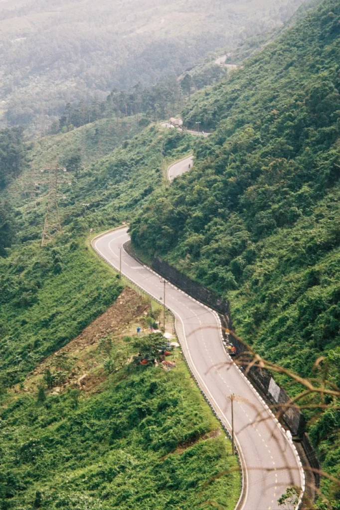Aerial view of a winding mountain road amidst greenery in Thua Thien Hue, Vietnam.