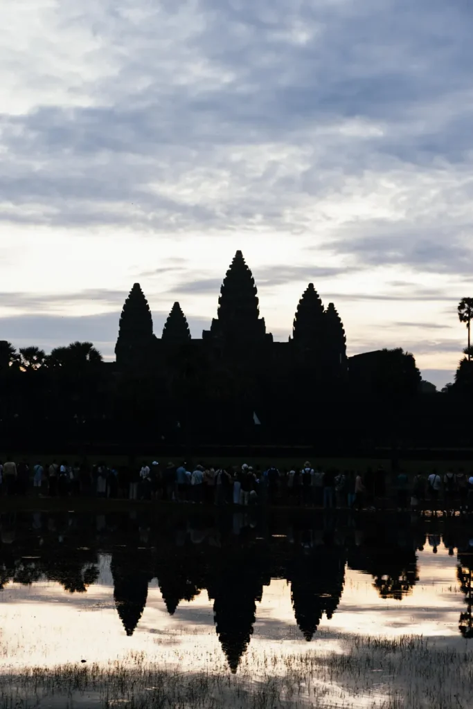 Angkor Wat silhouetted against the twilight sky, reflected in a pond, capturing a moment of serene beauty.