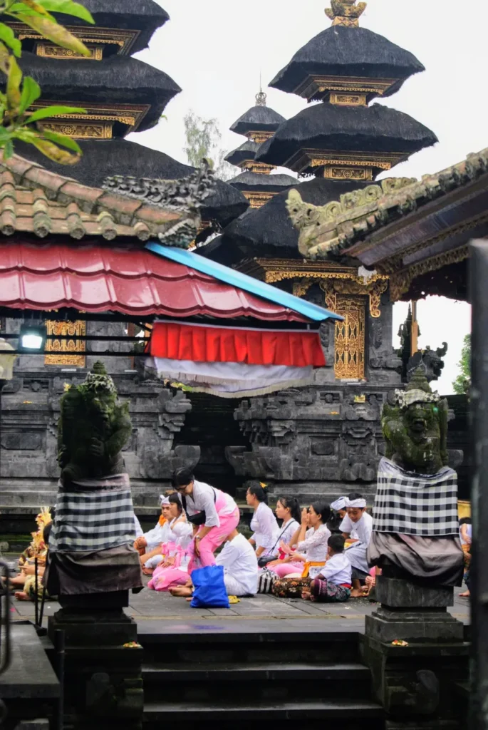 Balinese people in traditional attire participating in a ceremony at a temple in Bali, Indonesia.