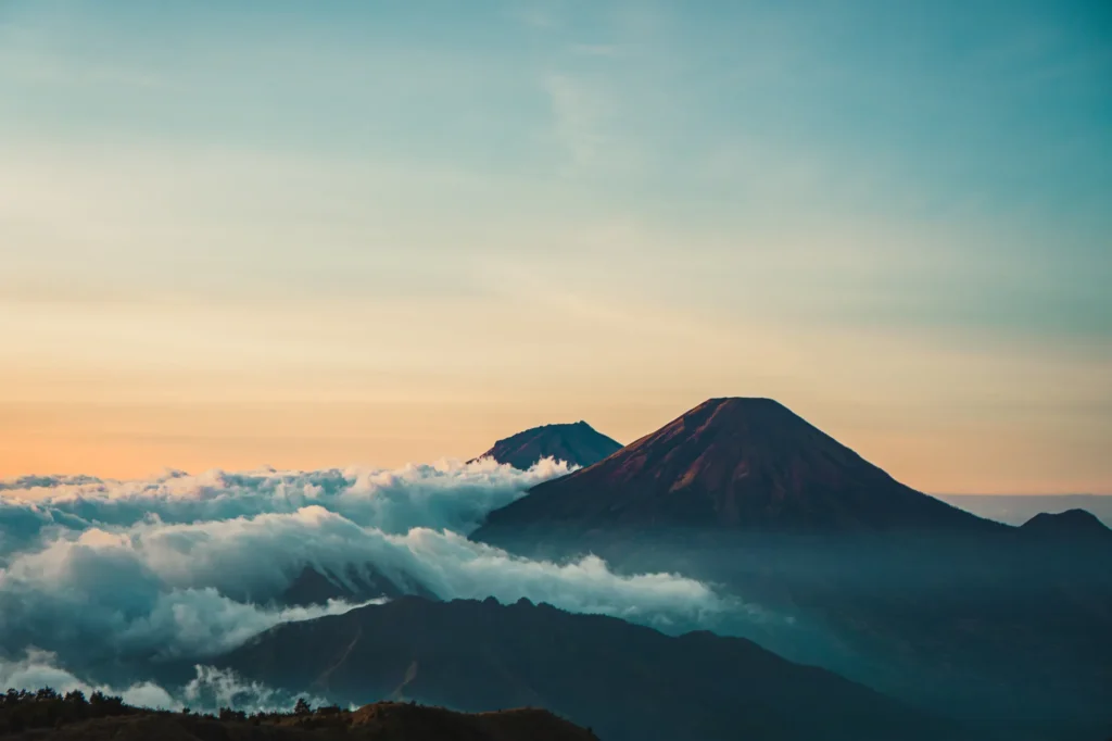 Beautiful sunrise view of Mount Sindoro with clouds and serene landscape in Java, Indonesia.