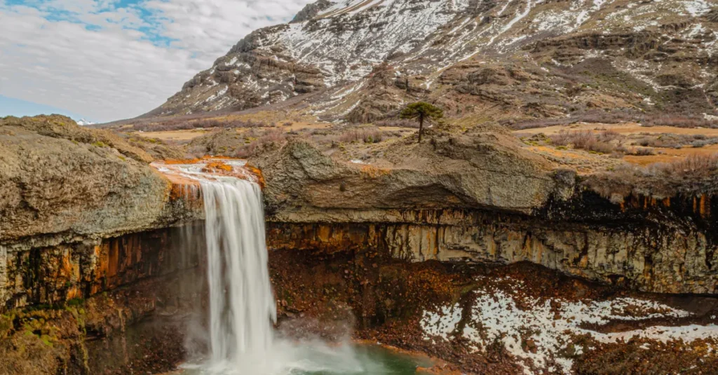 Saltos del Monday en couple : guide concret pour un day trip au Paraguay (sans pièges) Beautiful view of Salto del Agrio waterfall with snow-capped mountains in Neuquén, Argentina.