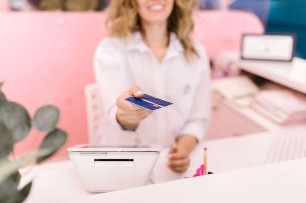 Blurred hands offering a credit card to a cashier at a modern retail counter.