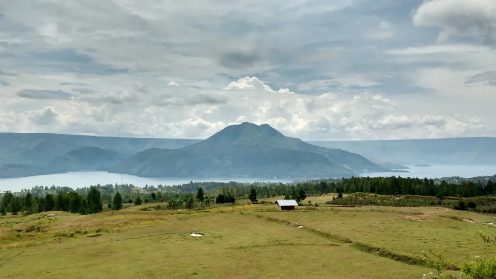 Breathtaking landscape of Lake Toba with mountains and lush green fields in Indonesia.