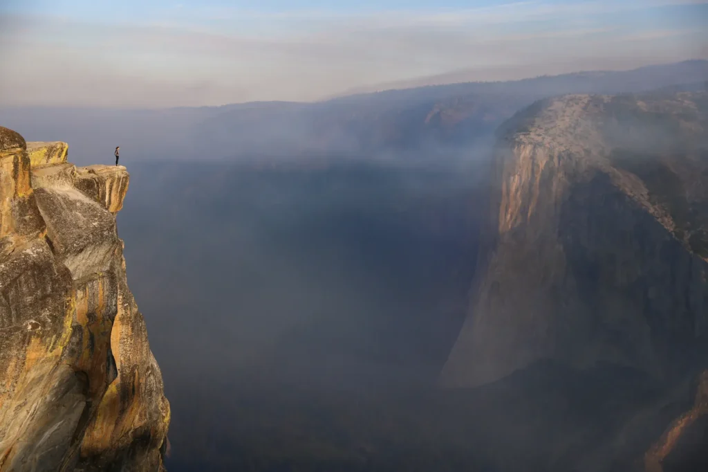 Breathtaking view of a lone hiker atop Taft Point in Yosemite National Park.