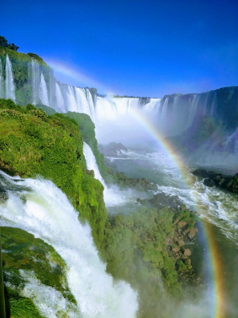 Breathtaking view of Iguazu Falls in Paraguay with vibrant rainbow and lush greenery.