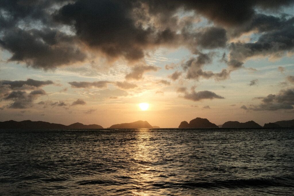 Captivating sunset over El Nido's islands in the Philippines, with dark clouds and calm ocean waters.