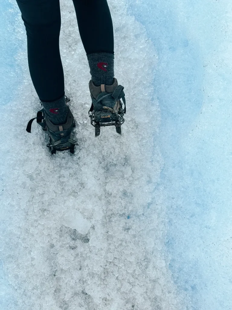 Close-up of a person hiking with crampons on the icy surface of Perito Moreno Glacier in winter.