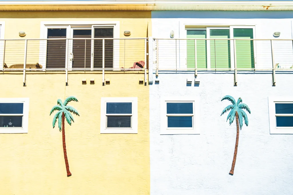 Colorful beachfront building wall featuring decorative palm trees and vibrant tones.