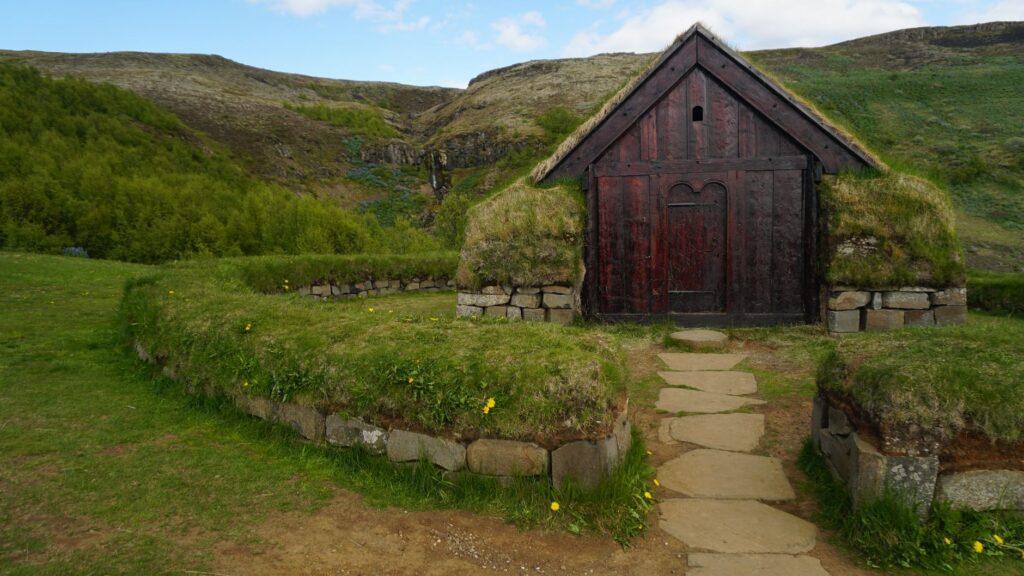 Discover a traditional Icelandic turf house amid a lush and serene landscape, offering a glimpse of historic architecture.