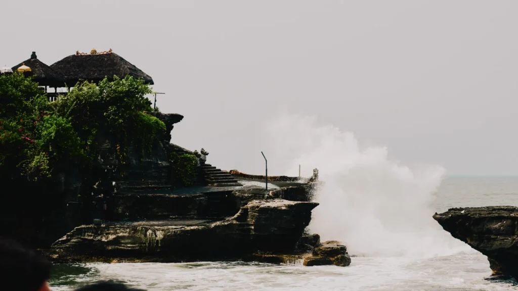 Dramatic waves crash against the cliffs of Tanah Lot Temple, a serene oceanfront view in Bali.