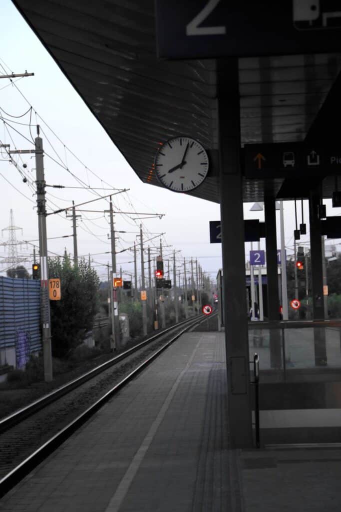Empty railway platform with clock and tracks at an Austrian train station.