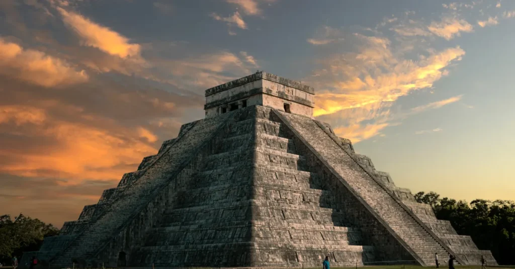 Chichén Itzá en couple depuis Cancún : le day-trip concret (avec les pièges à éviter) Majestic view of El Castillo pyramid at Chichen Itza with a vibrant sunset sky.