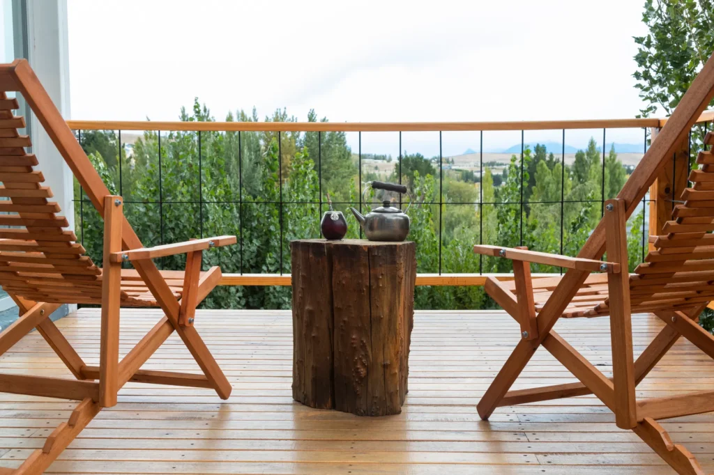 Relaxing wooden balcony with chairs and kettle offering a scenic view in El Calafate, Argentina.