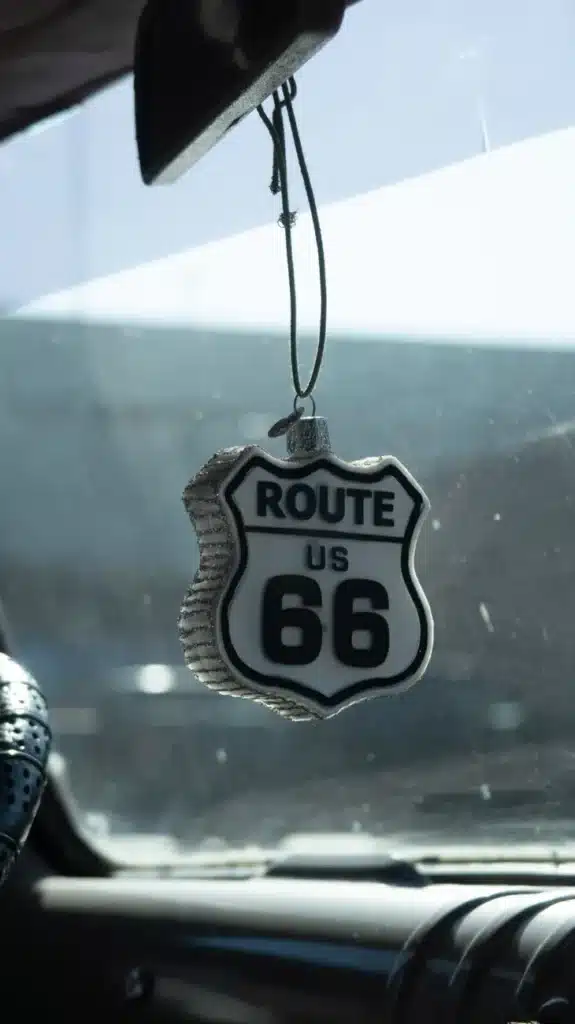 Route 66 sign hangs in the car interior, symbolizing a classic road trip experience.