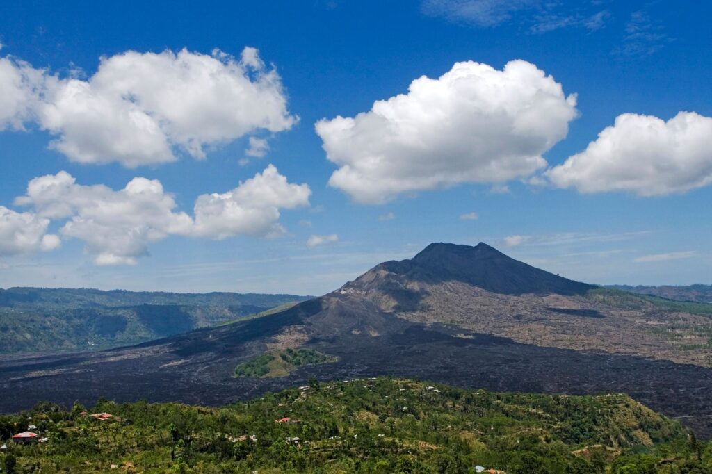 Scenic view of Mount Batur with bright blue skies and fluffy clouds in Bali, Indonesia.