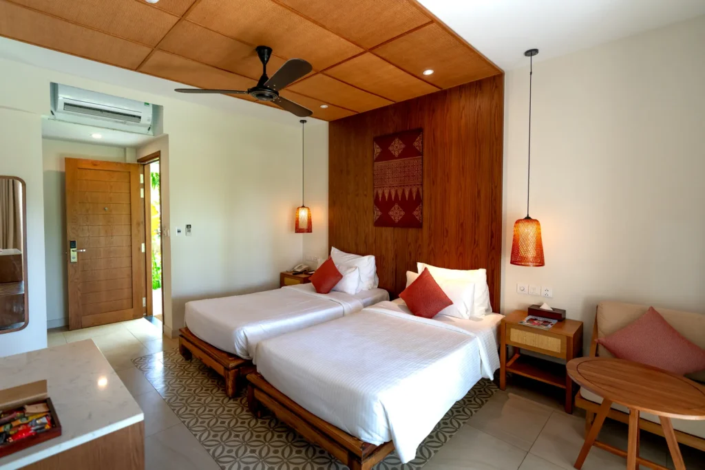 Spacious hotel room featuring twin beds, wooden decor, and modern amenities.