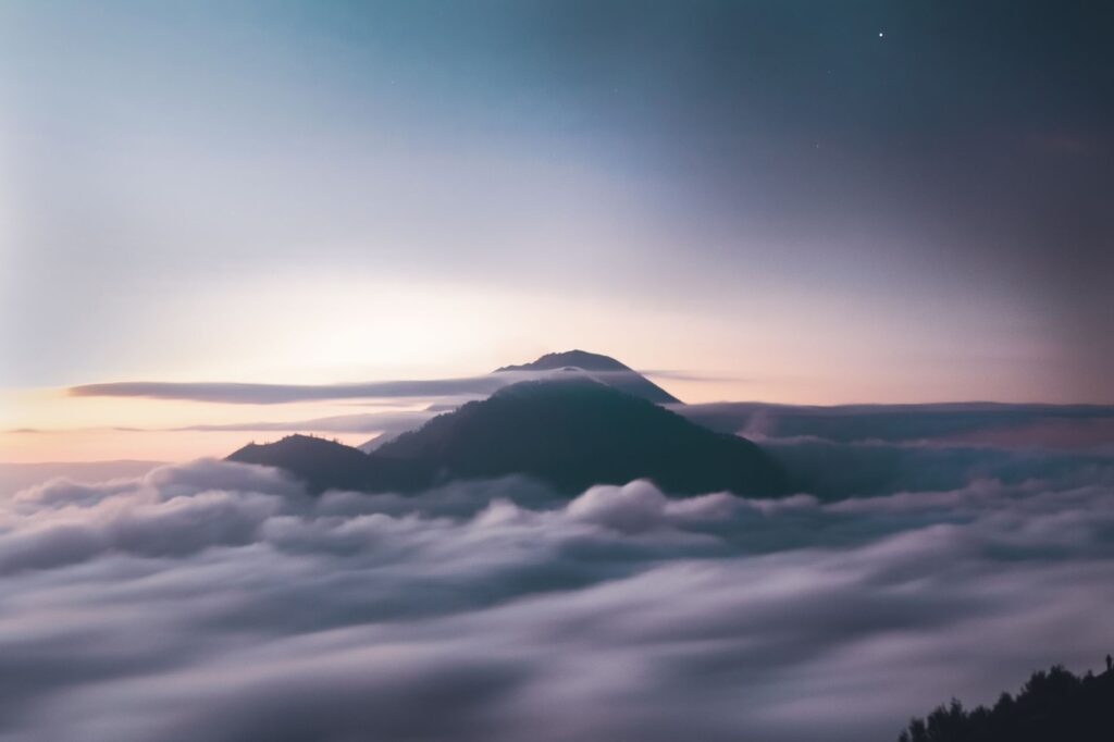 Stunning aerial view of a mountain in Bali wrapped in a sea of clouds at sunrise.