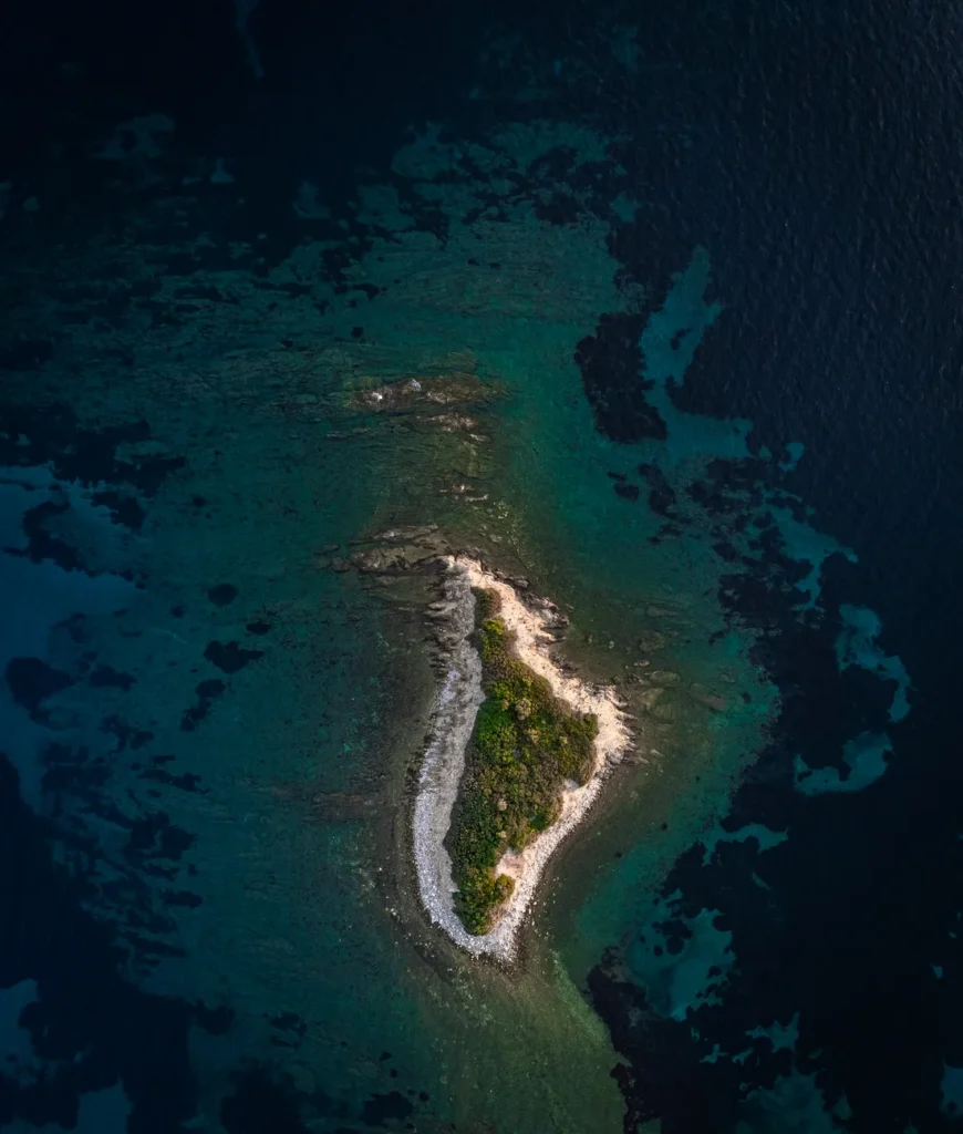 Stunning aerial view of a small, lush island surrounded by crystal-clear waters in Nikiti, Greece.