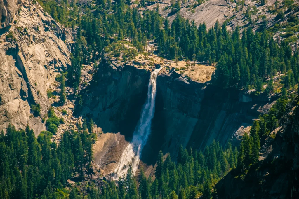Stunning aerial view of Vernal Fall cascading amidst lush green forests in Yosemite Valley.