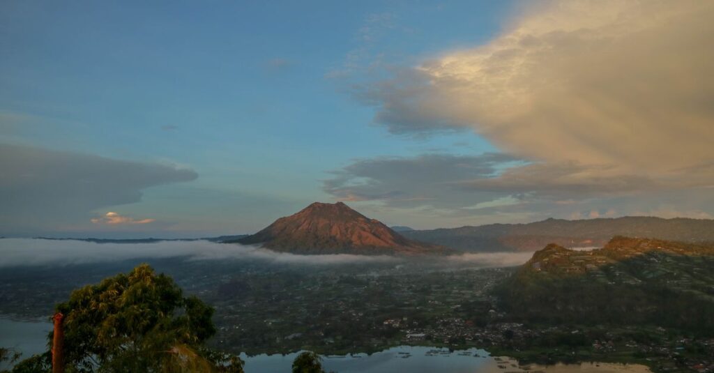 Kintamani à deux : volcans, lac Batur et lever de soleil sans se cramer Stunning view of Mount Batur in Bali at sunrise with dramatic clouds and mist.