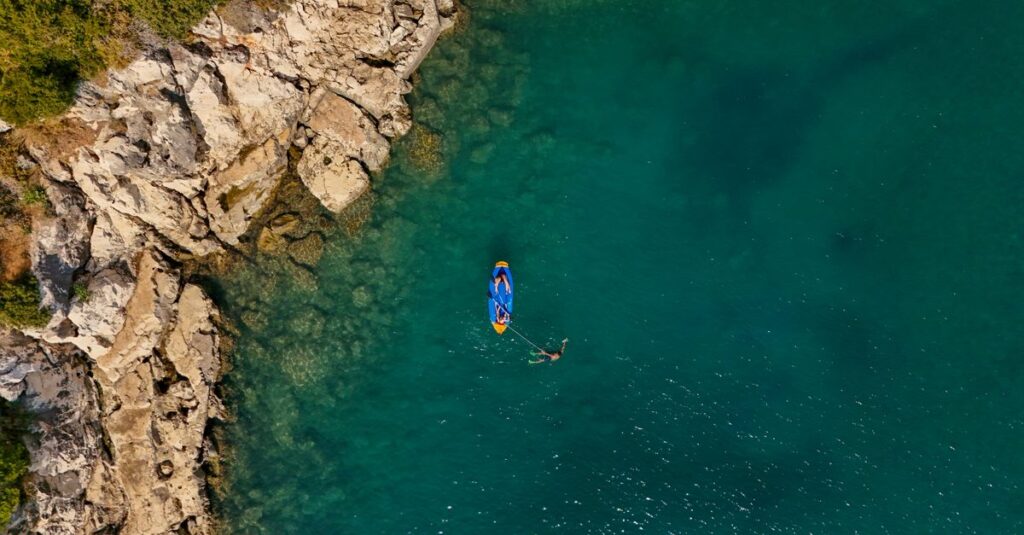 Kayak + rando sur Chinaman’s Hat (Mokoli‘i) à O‘ahu : le guide concret pour un moment canon à deux Top-down photo of a kayak floating by a rocky coast. Perfect for adventure and travel themes.