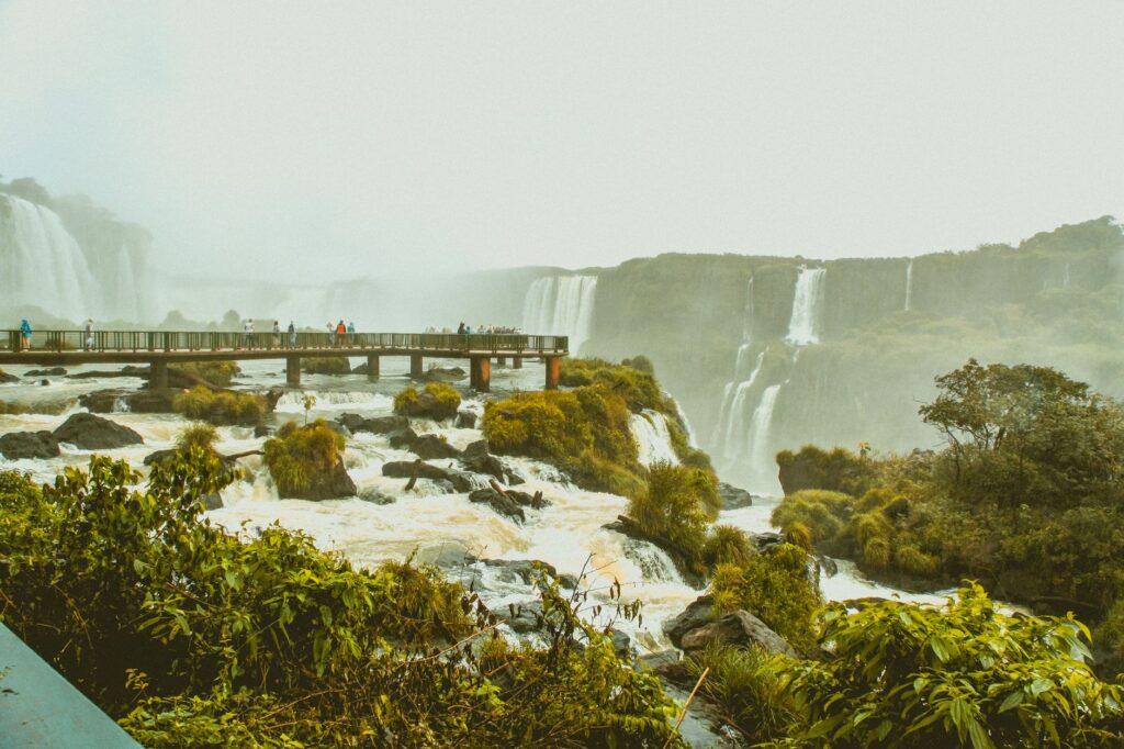Tourists explore the scenic bridge at Iguazu Falls amidst lush surroundings and cascading waterfalls.