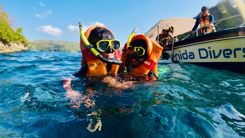 Two children snorkeling near Nusa Penida in Bali with life jackets and snorkel gear.