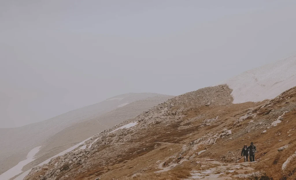 Two hikers walking on a rocky mountain path in Kosciuszko National Park, NSW, Australia.
