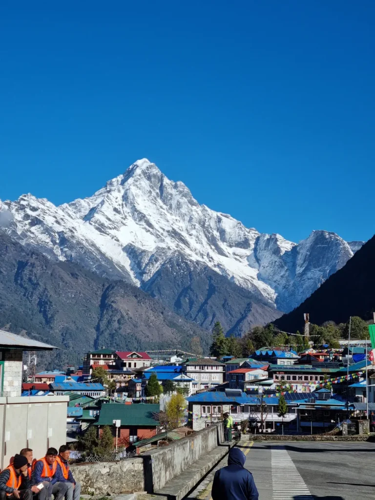 Vibrant Himalayan town under a stunning snow-capped mountain in clear blue sky.