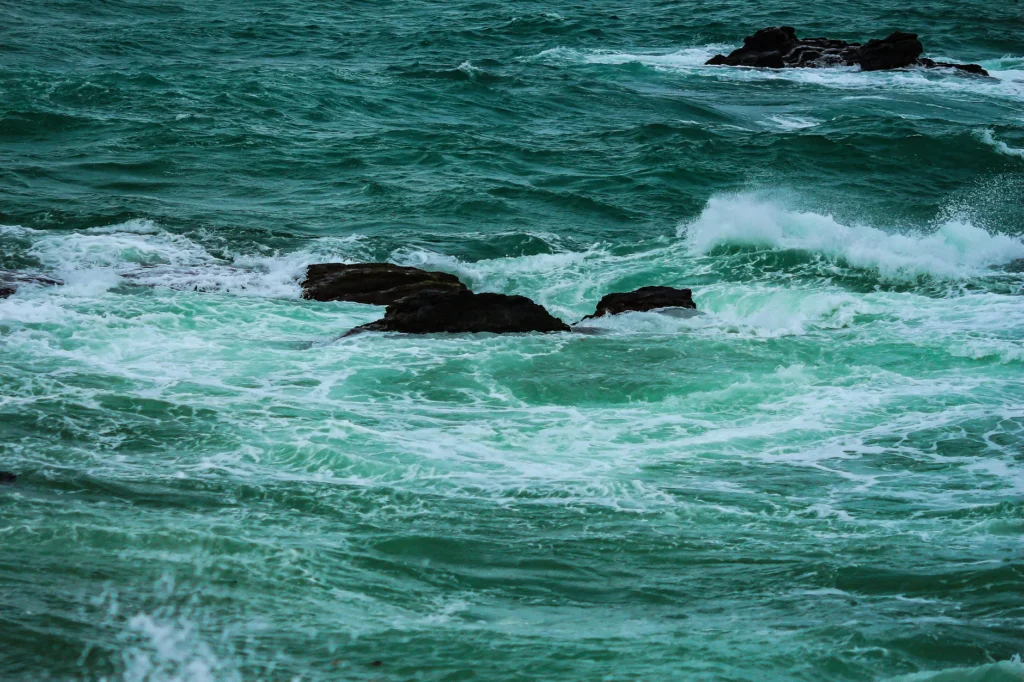 Vibrant ocean waves crashing against dark rocks in a dynamic seascape scene.
