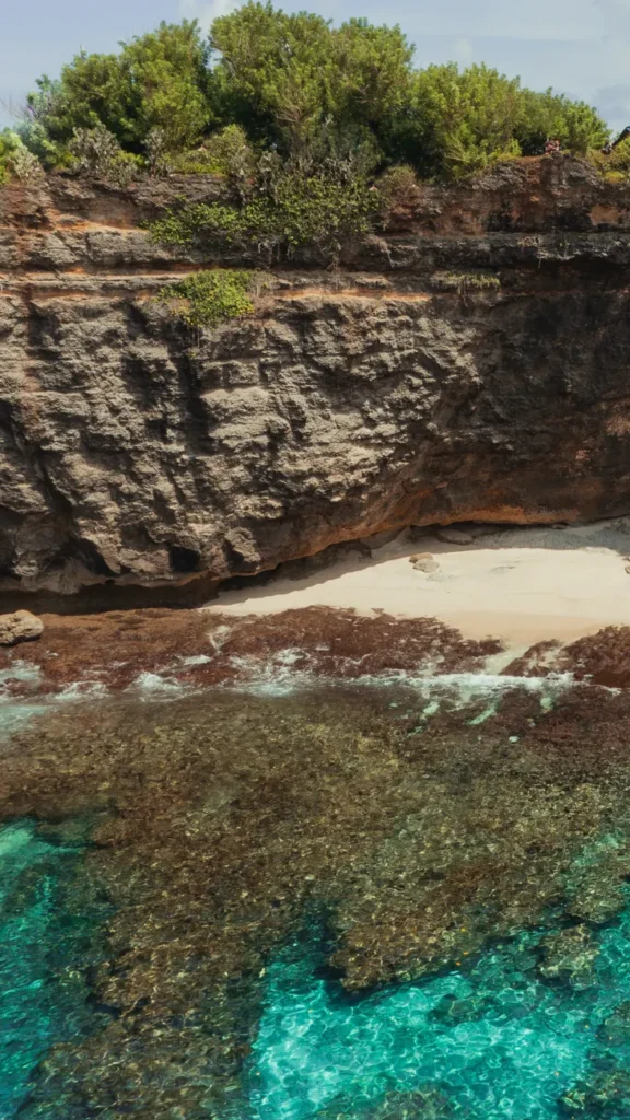A breathtaking aerial view of Nusa Penida's rocky coast with turquoise waters and lush greenery.