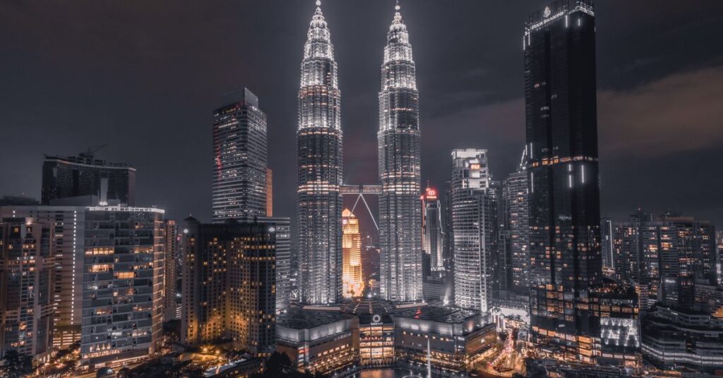 Kuala Lumpur en couple : le guide concret pour aimer la ville (sans la subir) A breathtaking night view of Kuala Lumpur's skyline featuring the illuminated Petronas Towers.