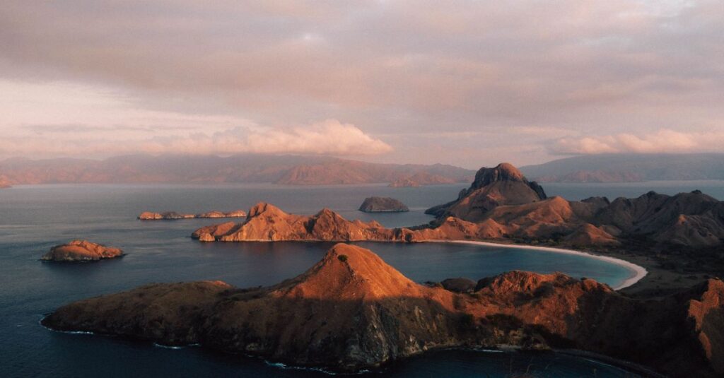 A breathtaking sunset view over the rugged coastline of Padar Island in Komodo National Park, Indonesia.