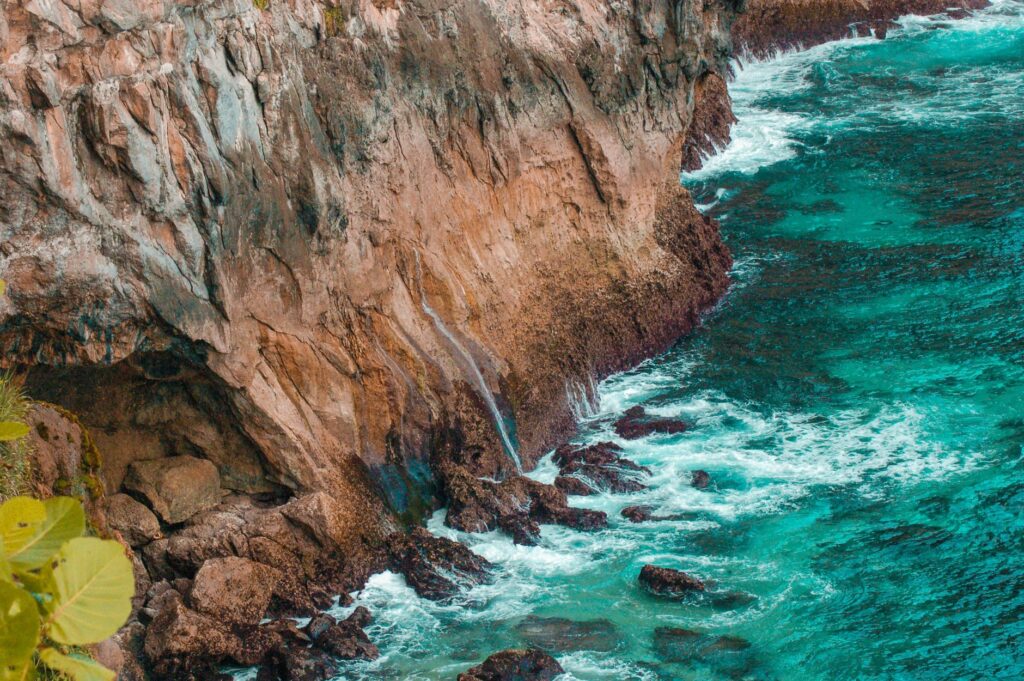 A breathtaking view of dramatic coastal cliffs with vibrant turquoise ocean waves below.